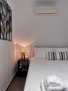 a bedroom with a white bed with a lamp on a night stand at Stone Steps Studio in Symi