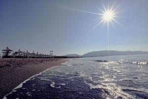 a beach with the sun shining over the water at Velipoja Grand Europa Resort, Affiliated by Meliá in Velipojë