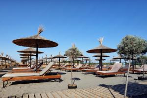 a row of lounge chairs and umbrellas on a beach at Velipoja Grand Europa Resort, Affiliated by Meliá in Velipojë