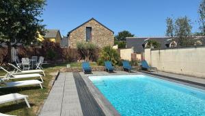 a swimming pool with blue chairs and a fence at Domaine Les Jardins dArsene in Tinténiac