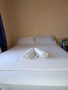 a white bed with two towels on top of it at Diani Escape in Ukunda
