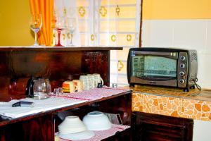 a kitchen with a microwave and glasses of wine at Diani Escape in Ukunda