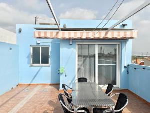 a table and chairs on the balcony of a blue house at Casa Pera Ático duplex 1ª in Chilches