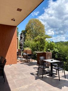 eine Terrasse mit Tischen, Stühlen und einem Sonnenschirm in der Unterkunft Ambient Hotel in Domžale