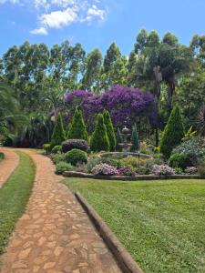 a path in a park with flowers and trees at Phumula Farm Guesthouse in Nhlangano
