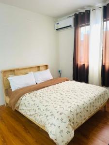 a bedroom with a bed with a comforter and a window at Sta Cruz Laguna Transient House in Santa Cruz