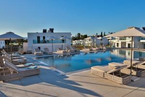 a large swimming pool with lounge chairs and umbrellas at Primelife Carvoeiro in Praia do Carvoeiro