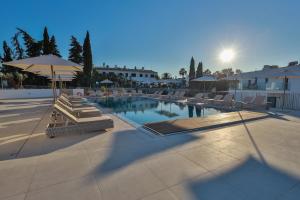 a swimming pool with lounge chairs and an umbrella at Primelife Carvoeiro in Praia do Carvoeiro