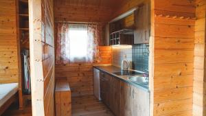 a kitchen with a sink in a wooden cabin at Domki Letniskowe Krakus in Rusinowo +82 photos