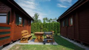 a couple of buildings with a bench between them at Domki Letniskowe Krakus in Rusinowo
