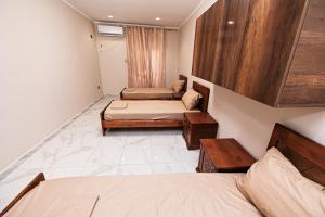 a small room with two beds and two tables at Hostel Bouchair Centre Ville Jijel in Jijel