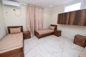 a room with two beds and a window at Hostel Bouchair Centre Ville Jijel in Jijel +2 photos