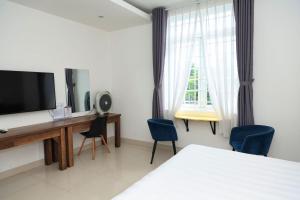 a bedroom with a bed and a desk with a television at Lucky Hotel in Phước Lai