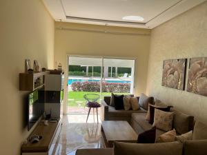 a living room with a couch and a table at Apparemment de luxe vue piscine in Bouznika