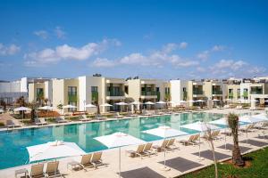 a pool with chairs and umbrellas in front of a hotel at Zephyr Saidia in Saïdia