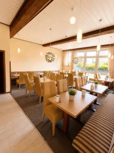 a dining room with tables and chairs and windows at Hotel Esingerhof by Alesta in Tornesch