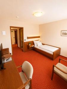 a hotel room with a bed and a desk at Hotel Esingerhof by Alesta in Tornesch