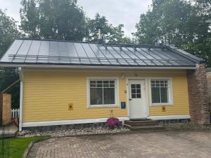 a yellow house with solar panels on the roof at Villa Tourula in Jyväskylä +6 photos