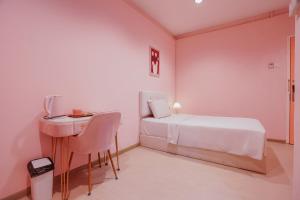 a white bedroom with a bed and a desk at Hugstore Pink Hotel in George Town