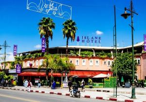 a building with palm trees in front of a street at Hotel Islane Médina in Marrakesh