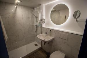a bathroom with a shower and a sink and a mirror at Urban House in Roubaix
