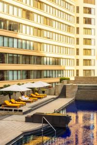 a building with tables and umbrellas and a pool of water at Trident Bandra Kurla in Mumbai