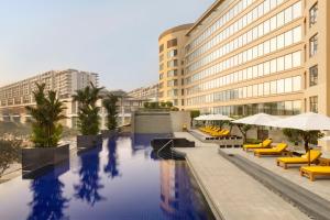 a hotel swimming pool with yellow chairs and buildings at Trident Bandra Kurla in Mumbai