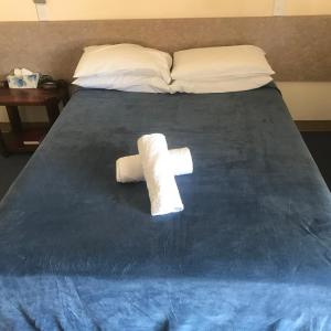 a bed with a white blanket and pillows on it at Nanango Star Motel in Nanango