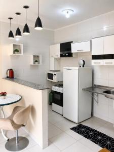 a white kitchen with a refrigerator and a table at Balcony house in Campo Grande
