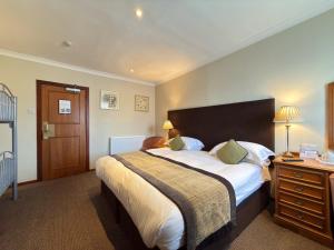a bedroom with a large bed with a wooden headboard at The Angus Hotel & Spa by Compass Hospitality in Blairgowrie +68 photos