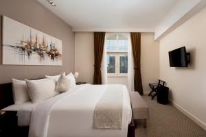 a bedroom with a large white bed and a window at Central Mansions Hotel and Apartments in Phnom Penh