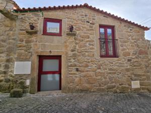 a stone building with red windows and a door at Casa da Caleira in Fonte Arcada