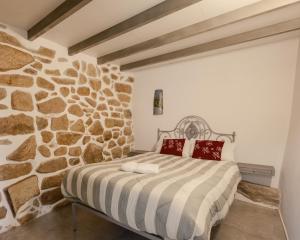 a bed in a room with a stone wall at Casa da Caleira in Fonte Arcada