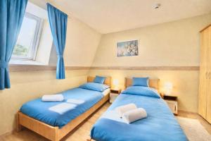 two beds in a room with blue curtains at Castle Park Suites in Hermina-major