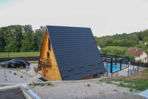 a house with a black roof and a swimming pool at Koliba & SPA SlaDjo in Brčko
