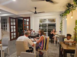 a group of people sitting at tables in a restaurant at Garden Rooms by Shams Thoddoo in Thoddoo