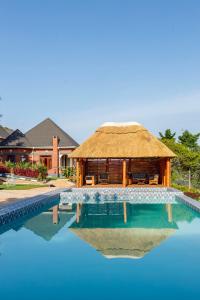 a house with a thatch roof and a swimming pool at Chui hidden Lodge Karatu in Karatu