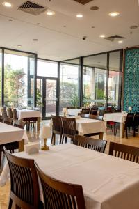 a restaurant with white tables and chairs and windows at Sen Otel in Sakarya