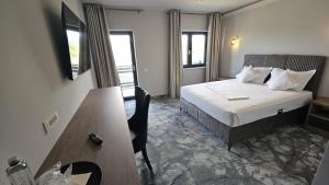 a hotel room with a bed and a desk and a table at Airport Hotel - Baia Mare - Maramures in Baia Mare +16 photos
