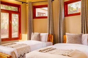 three beds in a room with windows at Chui hidden Lodge Karatu in Karatu +55 photos
