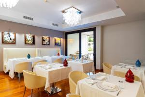 a restaurant with white tables and chairs and a chandelier at Relais Paradiso in Vietri sul Mare
