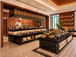 a chef standing behind a buffet in a restaurant at The Crown Puducherry in Pondicherry