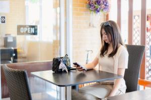a woman sitting at a table looking at her cell phone at JT Place Buriram in Buriram