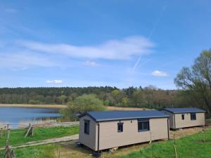 two cottages in a field next to a lake at Haus Barsch in Lohmen +10 photos