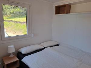 a white bedroom with a bed and a window at Haus Barsch in Lohmen