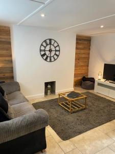 a living room with a couch and a clock on the wall at Bryndegwel in Saint Dogmaels, cardigan- river views, Free parking in Cardigan