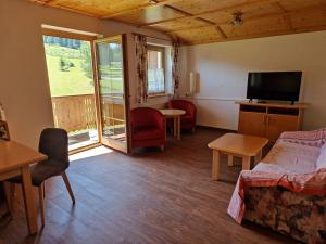 a living room with a bed and a tv at Gästehaus WOLFGARTEN in Sankt Jakob in Defereggen