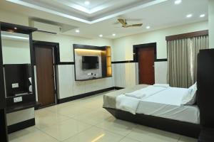 a bedroom with a bed and a flat screen tv at Kamath Yatri Nivas Plus in Māvalli
