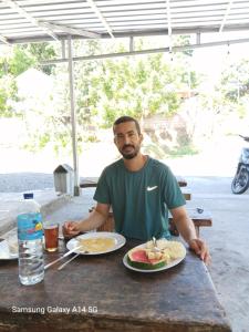 a man sitting at a table with a plate of food at 3Z Homestay in Bayan