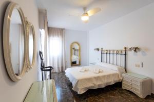 a white bedroom with a bed and a mirror at house las chuchas CALAHONDA in Motril
